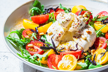 Close-up of burrata cheese salad with arugula and tomatoes.