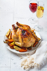Baked whole chicken stuffed with thyme, lemon and vegetables on white plate for wine.