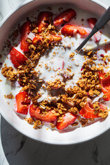 Granola with yogurt and strawberries in white bowl, close-up. Healthy breakfast concept.