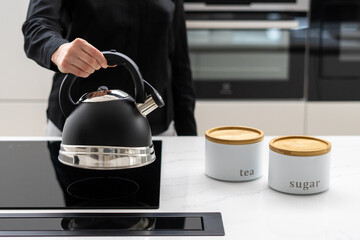 Woman holding kettle over ceramic induction stove