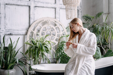 Young woman in bathrobe touching her hair