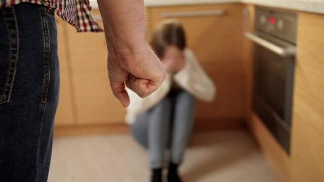Mad man beating and threating young woman crying on floor. Concept of domestic violence, parent abuse and family aggression.