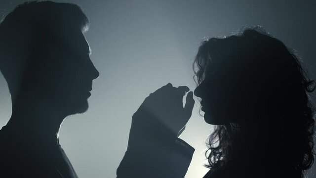 Silhouette couple touching each other indoors. Man woman with joined hands.