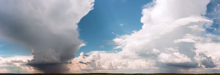 Air clouds in the blue sky. Nature background. Sunset sun. Warm evening. Sunset over the valley and slope. The rays of the sun through the cloud.