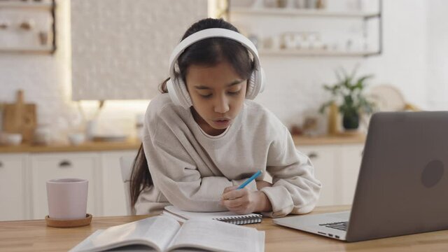Positive indian girl listening music studying at home
