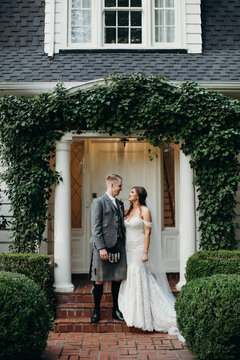 Bride and Groom Standing on Steps in front of Home on Wedding Day