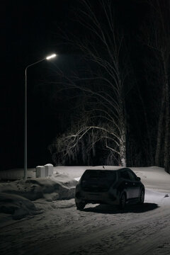 Electric car parked near charging station in winter countryside