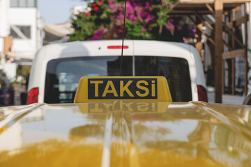 Bright yellow taxi sign on the roof of a yellow car on a sunny day. 