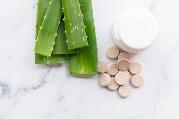 Aloe vera natural tablets. Freshly cut leaves with a pill bottle and tablets