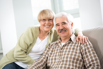 Happy elderly couple hugging at home and smiling