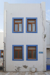 Fototapeta na wymiar A white building with blue window frames against a blue sky in the Greek style. Travel and architecture concept. High quality photo