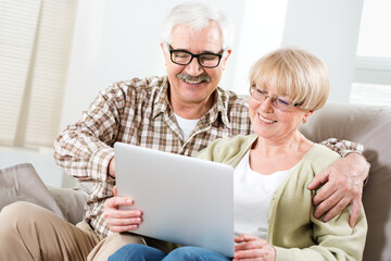Elderly couple talking using laptop together