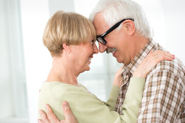 Elderly couple hugging at home and smiling
