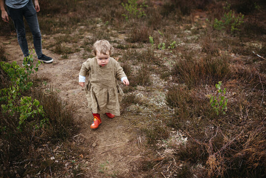 Little girl walking in the forst, dad is walking behind her