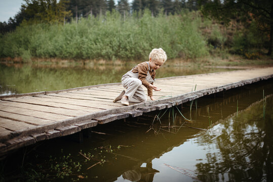 Toddler boy exploring nature and the life around a lake