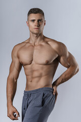 Fototapeta premium Bodybuilder showing his muscular body against gray background