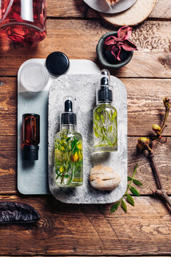 Aromatic oils with herbs in transparent bottles on wooden background