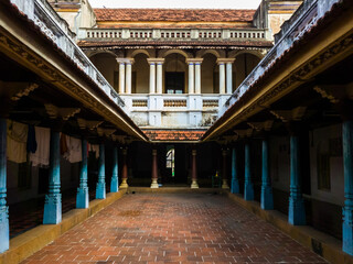 The inner courtyard lined with wooden pillars and columns of a heritage house in a Chettinadu...
