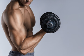Young and muscular bodybuilder man working out with dumbbells
