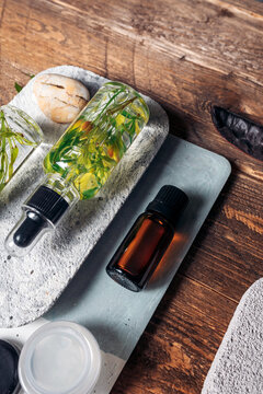 Aromatic oils with herbs in transparent bottles on wooden background