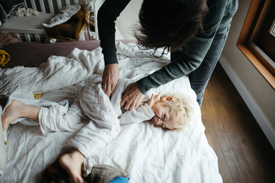 Father tickle his son on the bed