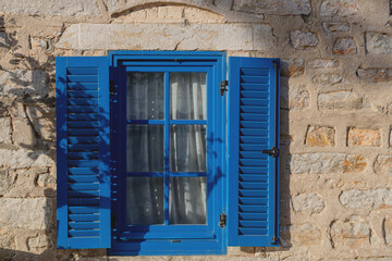 Obraz na płótnie Canvas A gray building with blue window frames in sunlight in the Greek style. Travel and architecture concept. Bodrum, Turkey
