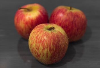 Three ripe red apples lie on a gray background