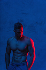 Bodybuilder is posing in the colorful neon light