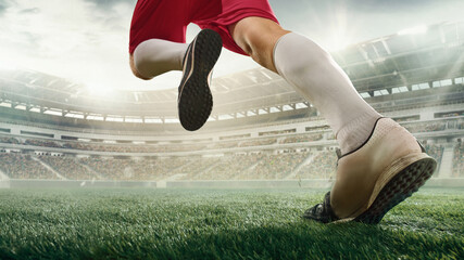 Cropped male soccer, football player in action, motion with ball at the stadium during sport match...