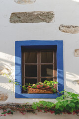 A white building with blue window frames and flowers on the windowsill. Travel and architecture concept. Bodrum, Turkey