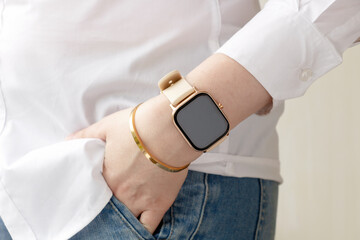 Young woman wear casual jeans and white classic shirt show hand with smartwatch and golden bracelet.