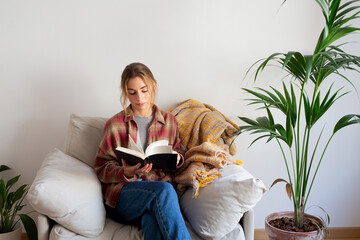 Young woman reading a book in sofa 