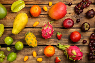 Many different delicious exotic fruits on wooden table, flat lay