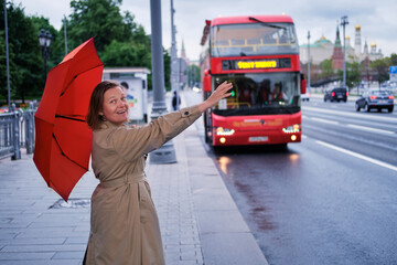 Adult woman with a red umbrella at a tourist bus near the Kremlin in Moscow, Russia