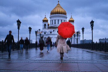 A woman with a red umbrella walks to the Cathedral of Christ the Savior