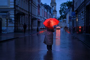 Fotobehang Een vrouw met een rode paraplu buiten een donkere stadsstraat © Андрей Журавлев