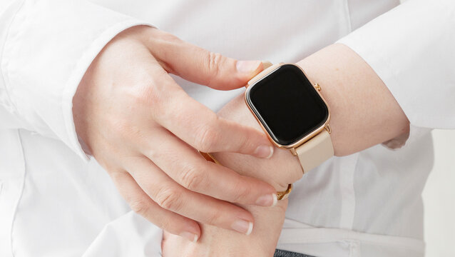 Smartwatch with black screen and neutral beige bracelet on himan hand above white classic shirt. Close up image, top view.