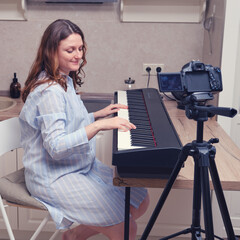 A woman in a home kitchen leads an online broadcast of a piano game on the Internet.