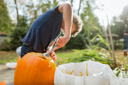  Boy scoops out pumpkin with spoon
