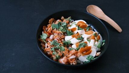 Salt egg spicy salad with dried shrimps on black background, Thai food breakfast.