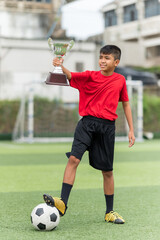 Asian Teenage soccer player holding a silver color trophy