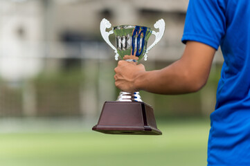 Asian Teenage soccer player holding a silver color trophy