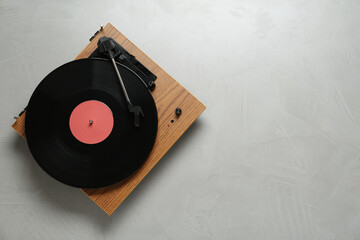 Turntable with vinyl record on light background, top view. Space for text