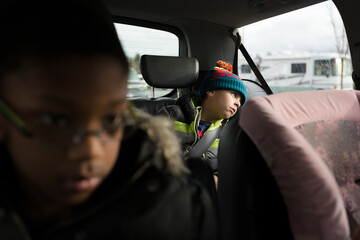 Boy in stocking cap slouches in back seat