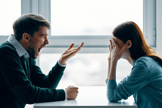 man and woman sitting at the table conflict emotions quarrel