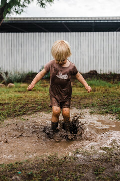 Female toddler splashing in mud puddle
