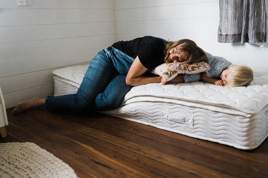 pregnant mother and daughter play on mattress