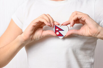 Flag of Nepal in the shape of a heart in the hands of a girl. Love Nepal. Respect for the people of Nepal