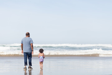 Father and daughter walk in ocean
