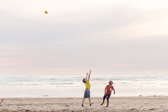 Brothers compete to catch football on beach
